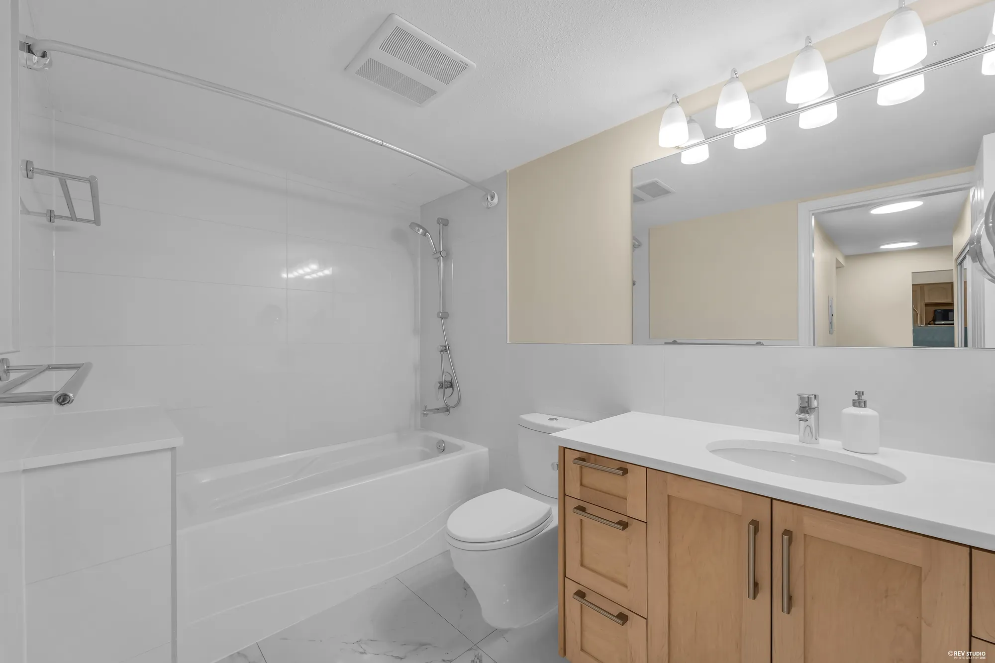 The 3-piece bathroom: tub-shower, oak vanity, mirror with a light bar
