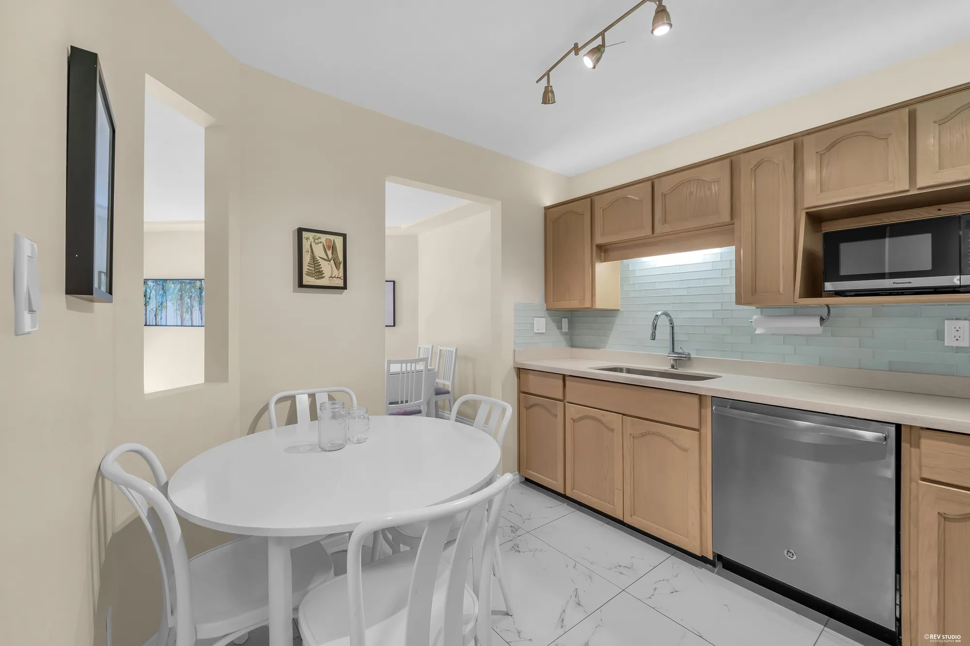 The kitchen from the dining area: oak cabinets, tile floor, stainless dishwasher