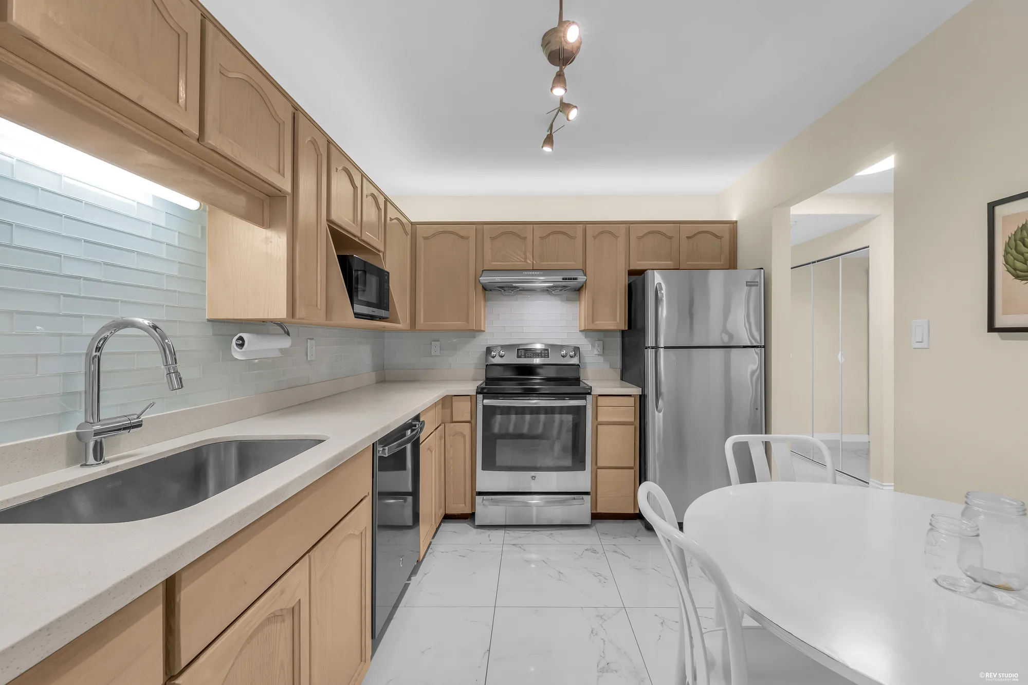 The kitchen run: sink, glass-tile backsplash, stainless stove and fridge